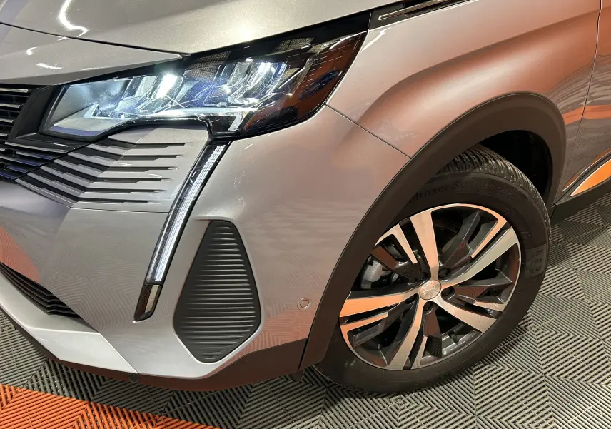 Gros plan sur l’avant droit gris du Peugeot 3008 Hybrid 2024, mettant en valeur le phare LED et la jante alliage.