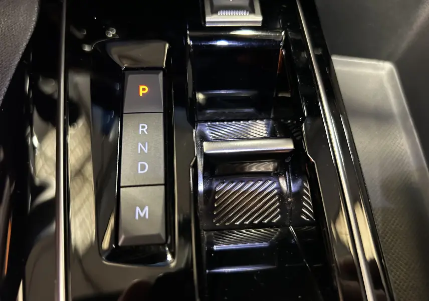 Gros plan sur la console centrale noire brillante du Peugeot 3008 Hybrid avec levier de vitesses automatique et indicateur P allumé.