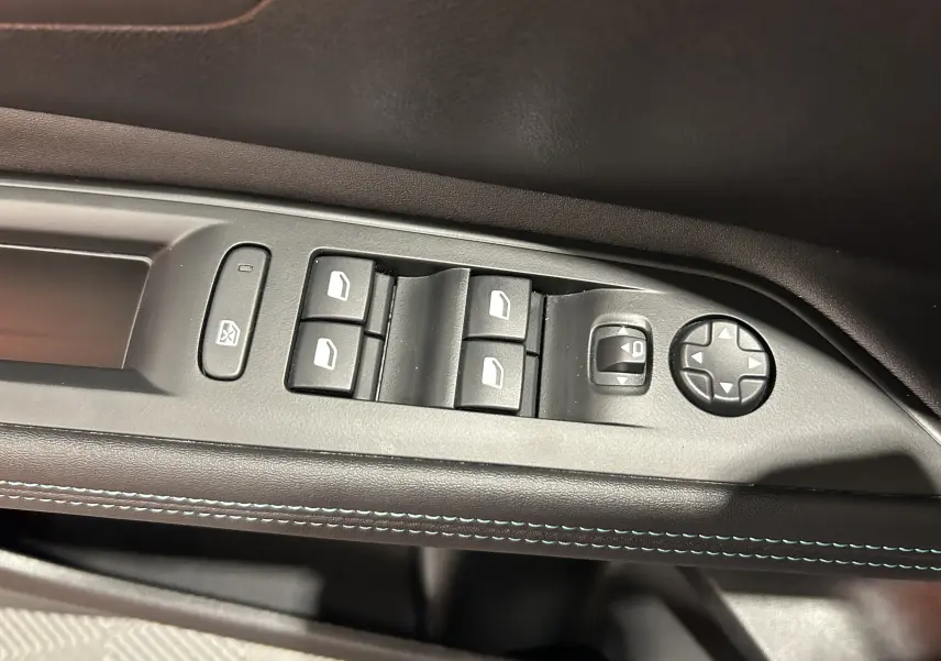 Commande des vitres électriques et réglage des rétroviseurs sur la porte côté gauche d’un Peugeot 3008 gris.