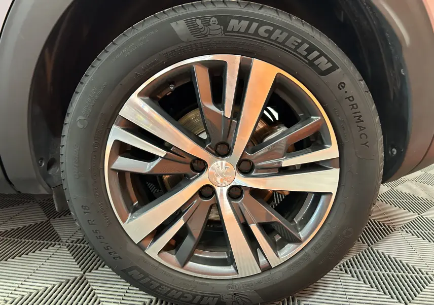 Gros plan sur la roue avant droite du Peugeot 3008 gris 2024, avec jante alliage et pneu Michelin e.Primacy.