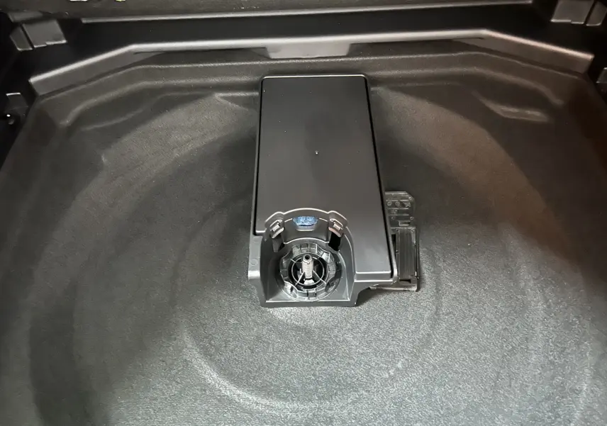 Vue rapprochée du coffre du Peugeot 3008 Hybrid 2024 montrant la trappe centrale et le revêtement gris foncé.