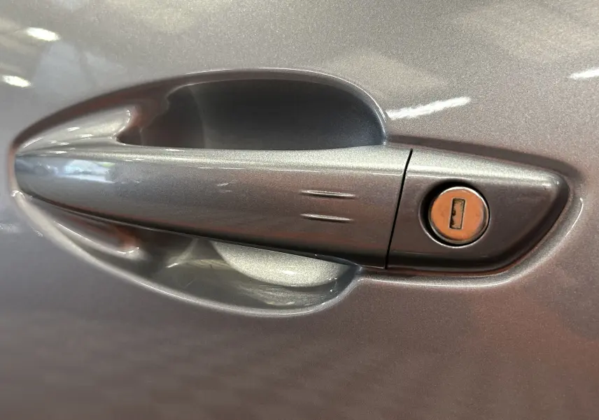 Poignée de porte côté droit gris métallisé du Peugeot 3008 Hybrid 2024 avec serrure intégrée visible.