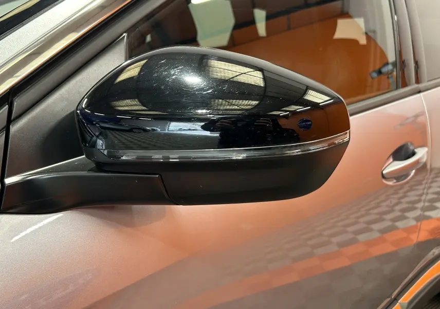 Gros plan sur le rétroviseur noir côté gauche du Peugeot 3008 gris, avec reflet de l'éclairage intérieur visible.