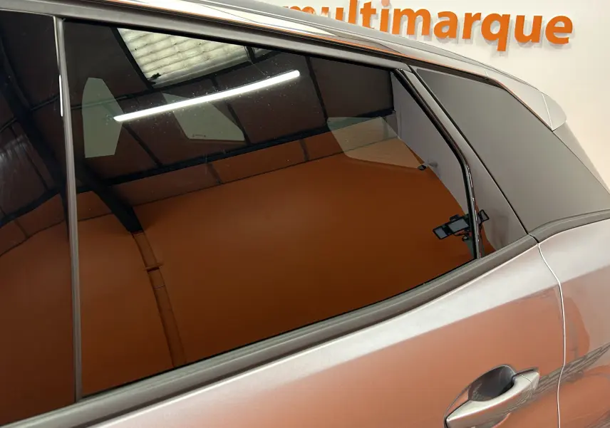 Détail sur la porte arrière côté droit d’un Peugeot 3008 gris 2024 avec vitre teintée et poignée intégrée.