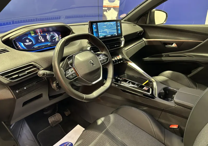 Vue intérieure côté conducteur du Peugeot 3008 Hybrid gris 2024, avec tableau de bord numérique et écran central GPS.