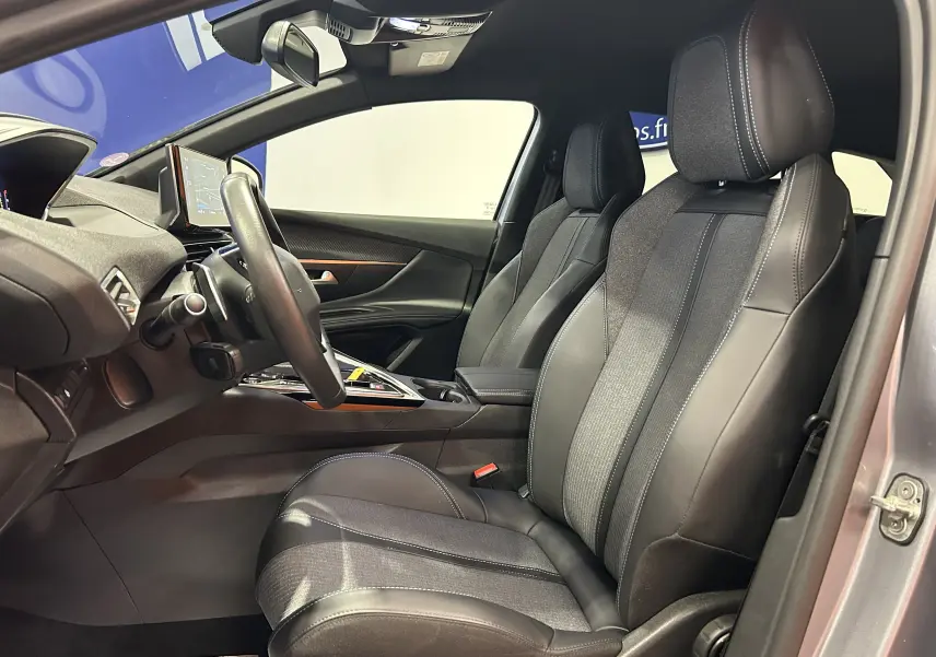Vue intérieure côté conducteur du Peugeot 3008 gris 2024, avec sièges cuir et tissu, volant multifonction et écran GPS intégré.