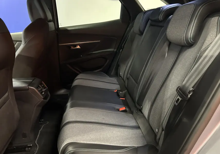 Vue intérieure côté droit des sièges arrière bi-matière gris et noir du Peugeot 3008 Hybrid 2024 avec appuie-têtes ajustables.