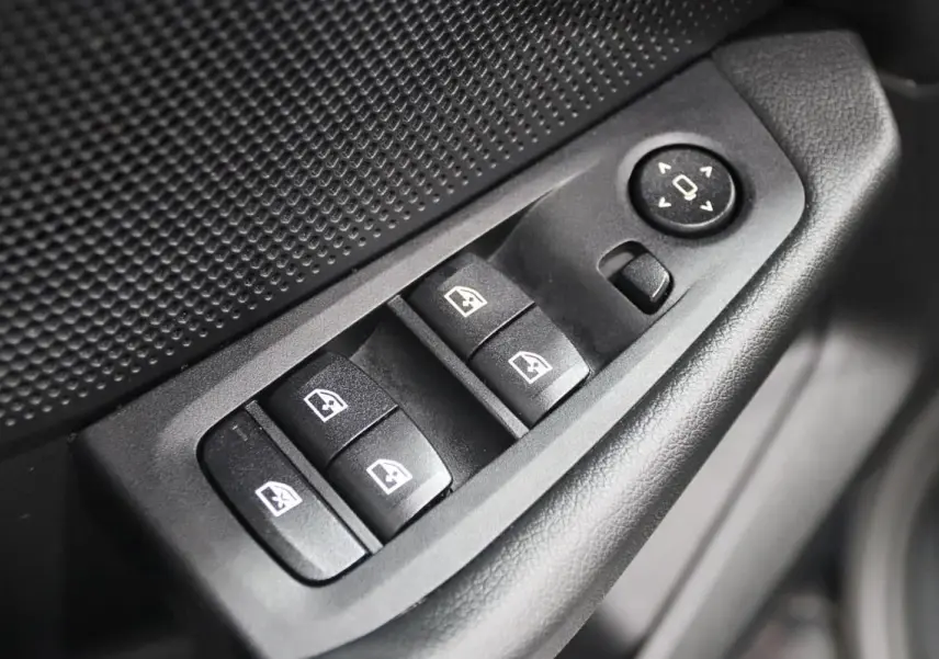 Gros plan sur les commandes de lève-vitres et réglage des rétroviseurs côté conducteur d'une BMW Série 1 noire.