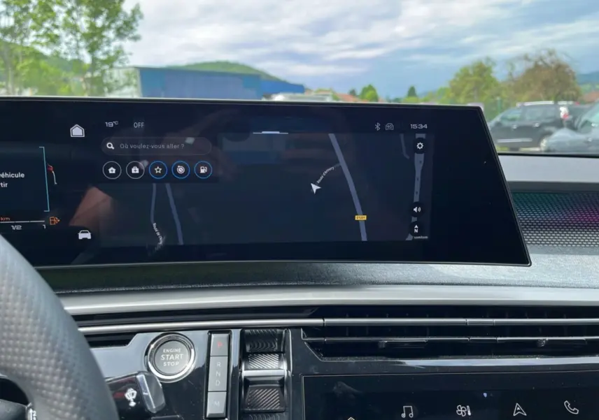 Vue intérieure du tableau de bord du Peugeot 5008 Hybrid 145 GT, écran tactile central avec navigation affichée.