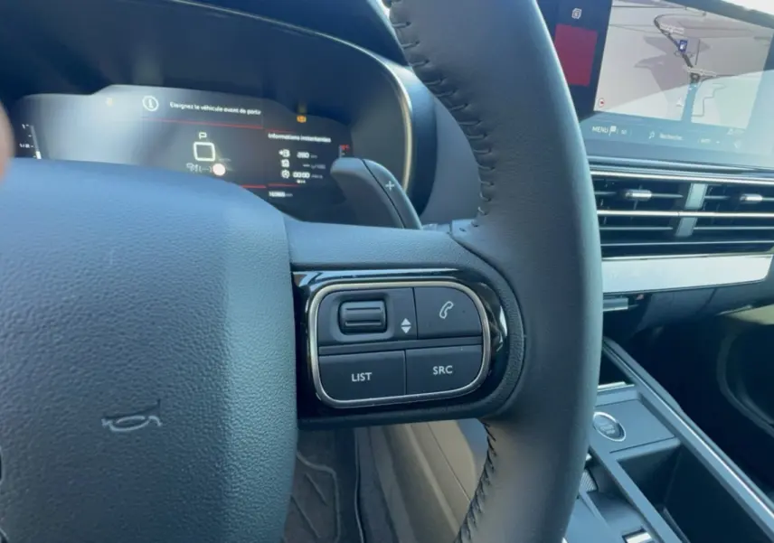 Gros plan sur le volant cuir multifonctions côté gauche du Citroën C5 Aircross 2025 avec écran tactile et tableau de bord numérique.