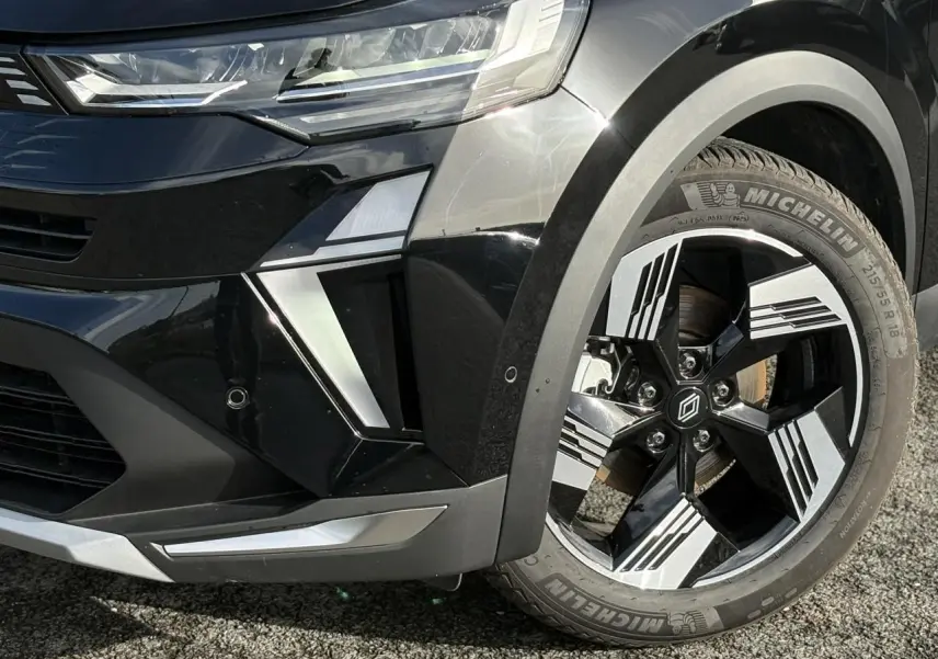 Gros plan sur l’avant droit noir étoilé du Renault Symbioz 2025, mettant en valeur la jante 18 pouces Gravity et le phare LED.