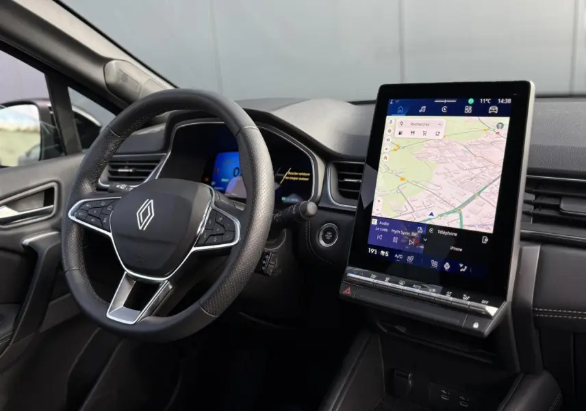 Vue intérieure côté conducteur du Renault Symbioz 2025, volant multifonction et écran tactile vertical avec navigation affichée.