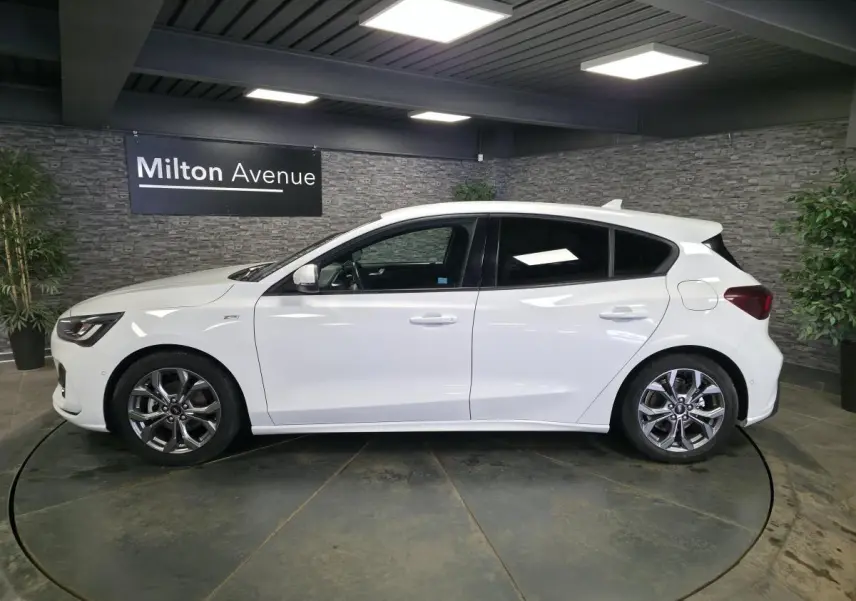 Vue de profil côté gauche d'une Ford Focus blanche 2024 finition ST Line avec jantes alliage et vitres surteintées.