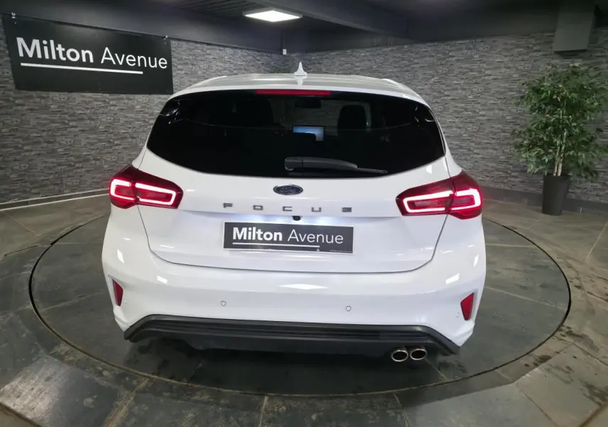 Vue arrière d'une Ford Focus blanche 2024 avec feux LED allumés, double sortie d'échappement et logo FOCUS centré.