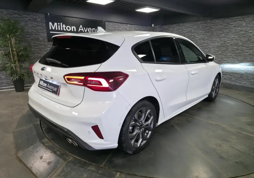 Vue 3/4 arrière droite d'une Ford Focus blanche 2024 avec feux LED et double sortie d'échappement sport.
