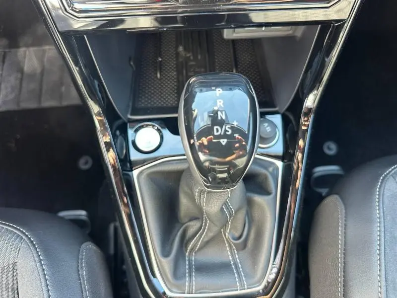 Gros plan sur le levier de vitesses automatique noir brillant du Volkswagen T-Cross gris cendré, entouré de garnitures noires.