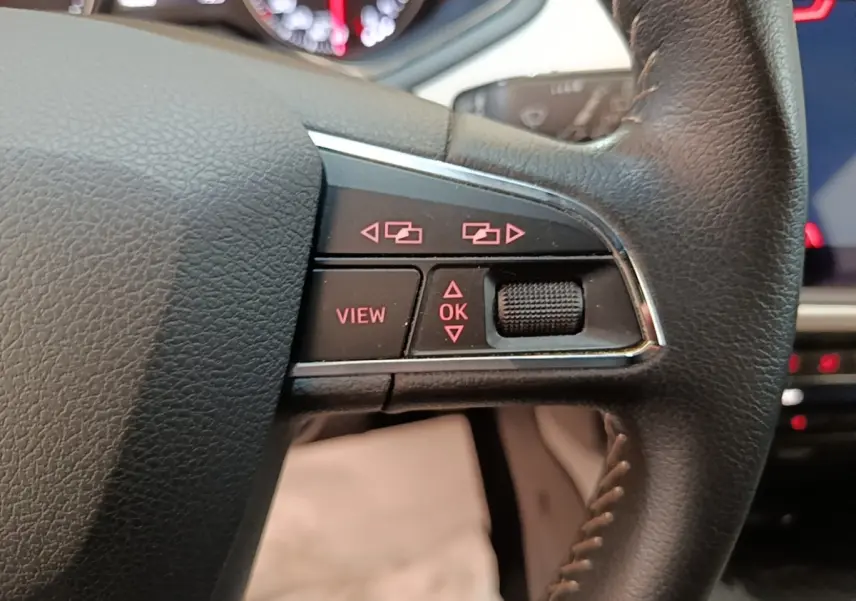 Gros plan sur les commandes à droite du volant cuir noir du SEAT Arona 2019, avec affichage digital en arrière-plan.