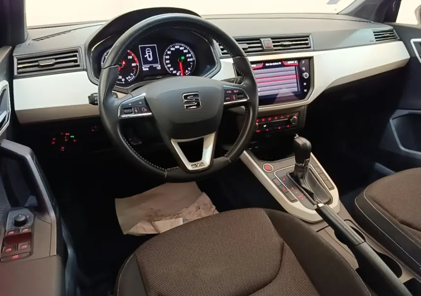 Intérieur du SEAT Arona 2019 vu côté conducteur, volant cuir, tableau de bord clair et écran tactile central.