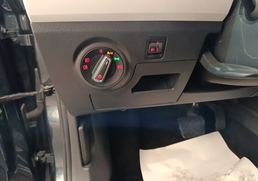 Gros plan sur la commande des phares à gauche du tableau de bord d’un SEAT Arona gris clair, intérieur noir.
