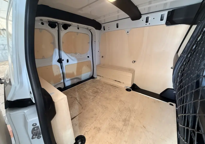 Vue intérieure arrière du Renault Kangoo blanc 2022, montrant l'espace de chargement avec parois et sol en bois.