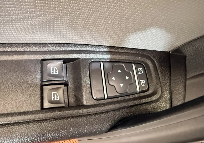 Gros plan sur les commandes des vitres et des rétroviseurs du côté conducteur d’un Renault Kangoo blanc 2022.