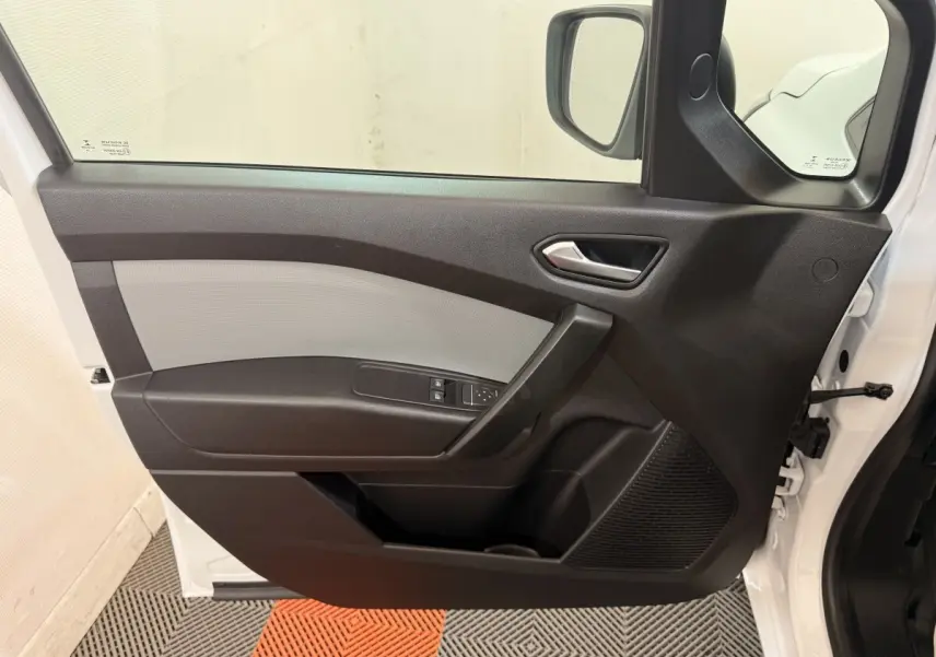 Vue intérieure de la porte avant gauche du Renault Kangoo blanc 2022, avec commandes de vitres et poignée noire.