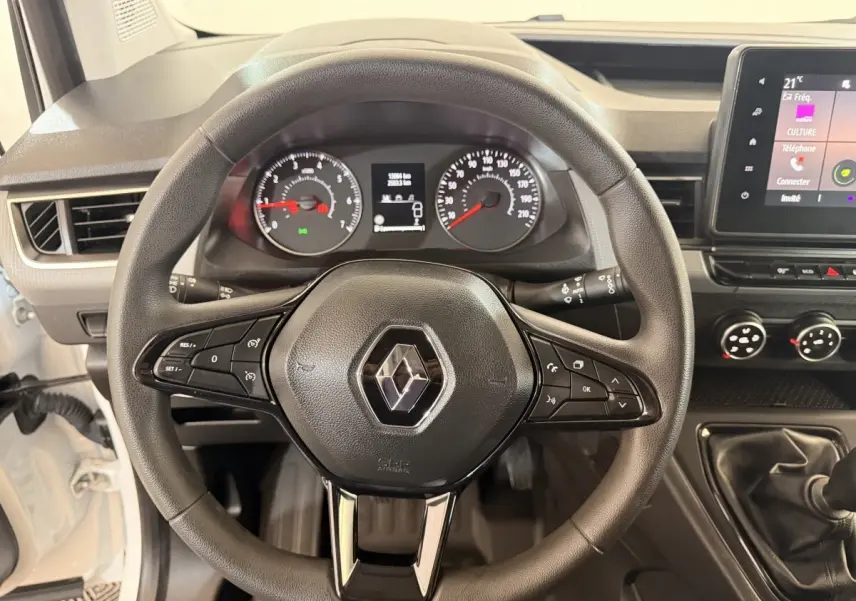 Vue intérieure centrée sur le volant noir du Renault Kangoo blanc 2022 avec tableau de bord et levier de vitesse manuel.