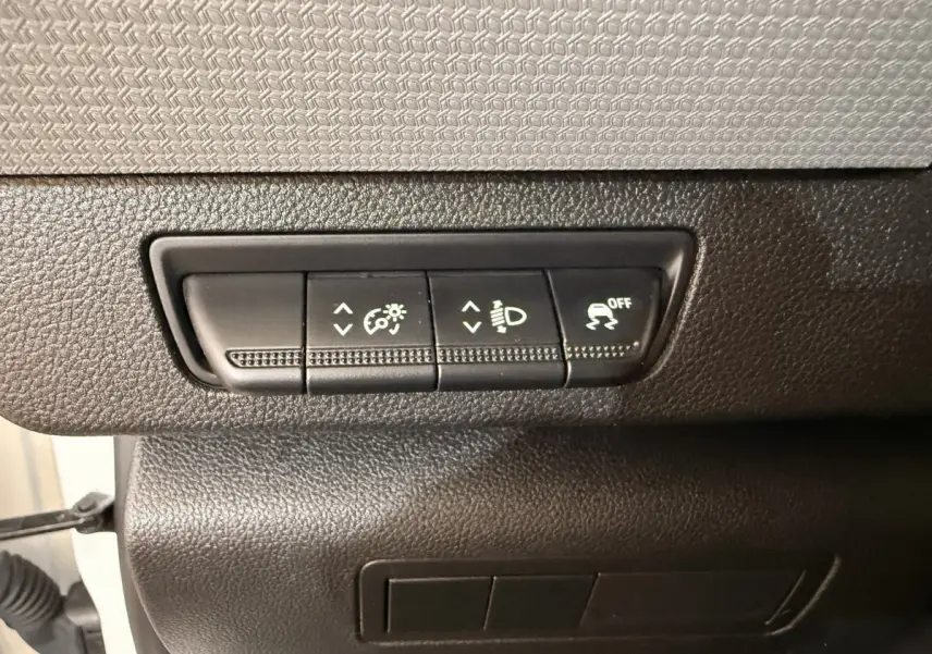 Gros plan sur les commandes de réglage d’éclairage et de traction du tableau de bord d’un Renault Kangoo blanc de 2022.