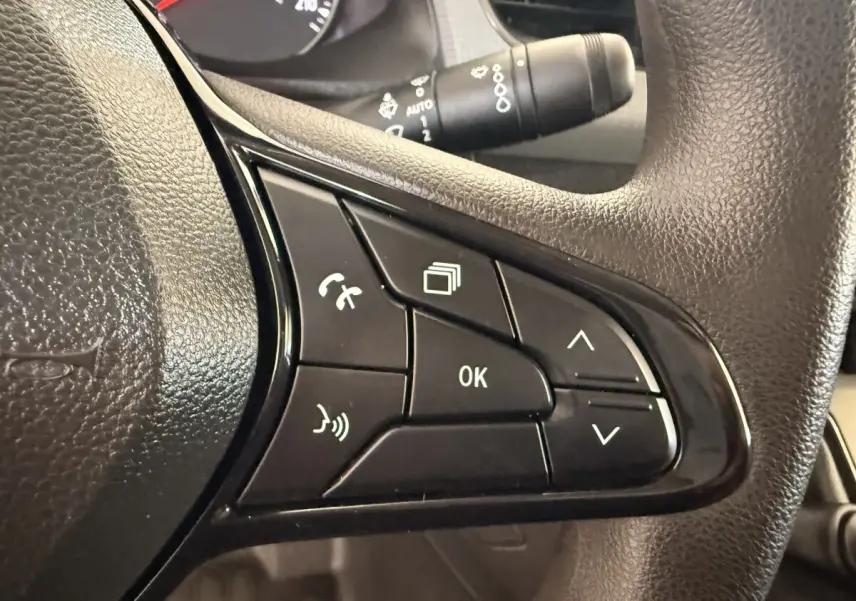 Gros plan sur les commandes multifonctions noires du volant du Renault Kangoo blanc de 2022, avec boutons de téléphone et navigation.
