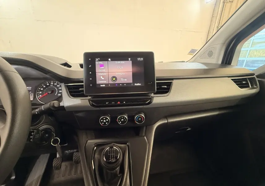 Vue intérieure du tableau de bord du Renault Kangoo blanc 2022, avec écran tactile central et levier de vitesse manuel visible.