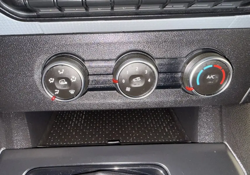 Gros plan sur les commandes de climatisation noires du Renault Kangoo blanc 2022, avec réglages manuels visibles.