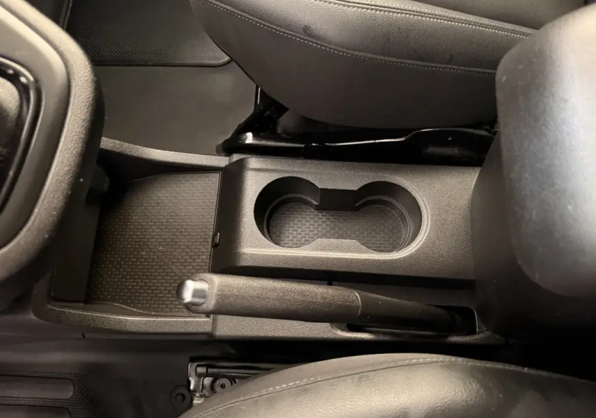 Vue rapprochée de la console centrale noire du Renault Kangoo 2022, montrant le frein à main manuel et deux porte-gobelets.
