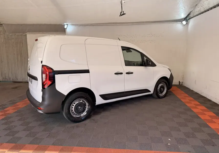 Renault Kangoo blanc vue de profil droit en intérieur, fourgonnette utilitaire avec protections noires sur les bas de caisse.