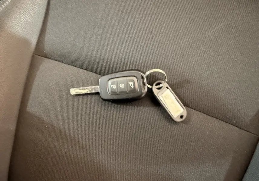 Clé de voiture Renault Kangoo 2022 posée sur un siège en tissu noir, sans vue du véhicule visible.