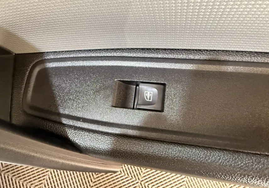 Bouton de commande de lève-vitre électrique sur la porte intérieure d'un Renault Kangoo blanc, vue rapprochée.