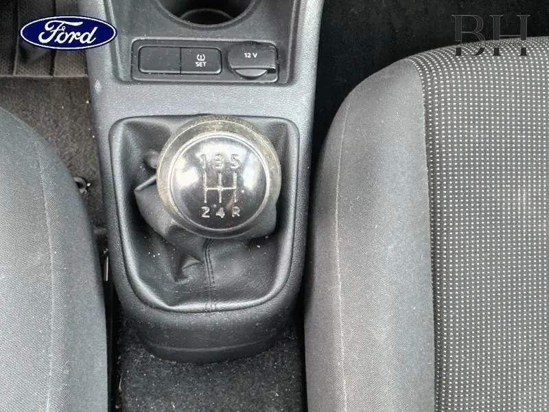 Le levier de vitesse manuel noir vu de dessus entre les sièges avant en tissu dots noir titane d'une Volkswagen Up blanche.