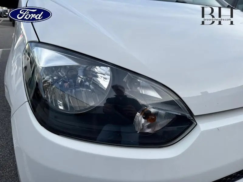 Gros plan sur le phare avant droit blanc candy d'une Volkswagen Up 1.0 60ch Concept! 2014.