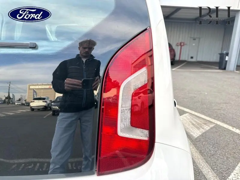 Feu arrière droit d'une Volkswagen Up blanche Candy vue de près sur un parking extérieur.