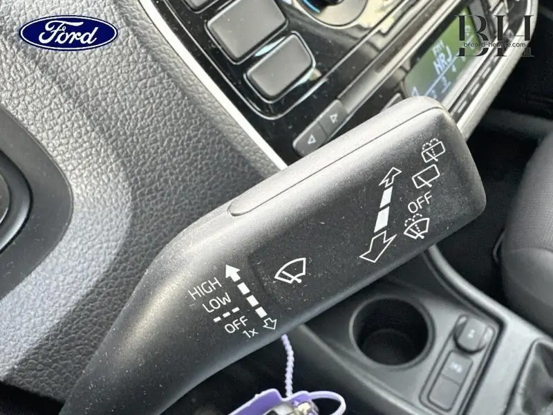 Gros plan sur la commande des essuie-glaces dans l'habitacle d'une Volkswagen Up blanche, montrant les réglages en blanc sur noir.