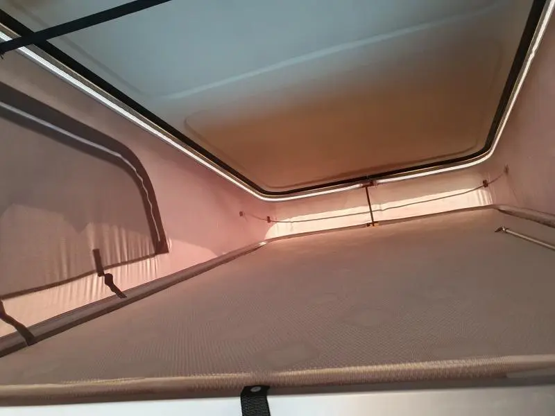 Vue intérieure du couchage en toile beige du Renault Trafic Fourgon L2H1, montrant la structure et la toile du toit relevable.