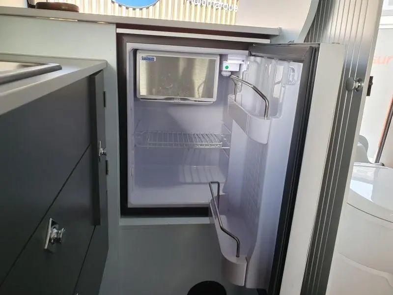 Vue intérieure du fourgon Renault Trafic L2H1 2022, montrant un petit réfrigérateur blanc ouvert dans l'aménagement intérieur.