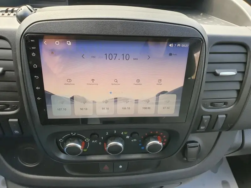 Vue rapprochée de l'écran tactile et des commandes de climatisation du tableau de bord du Renault Trafic Fourgon blanc Glacier 2022.