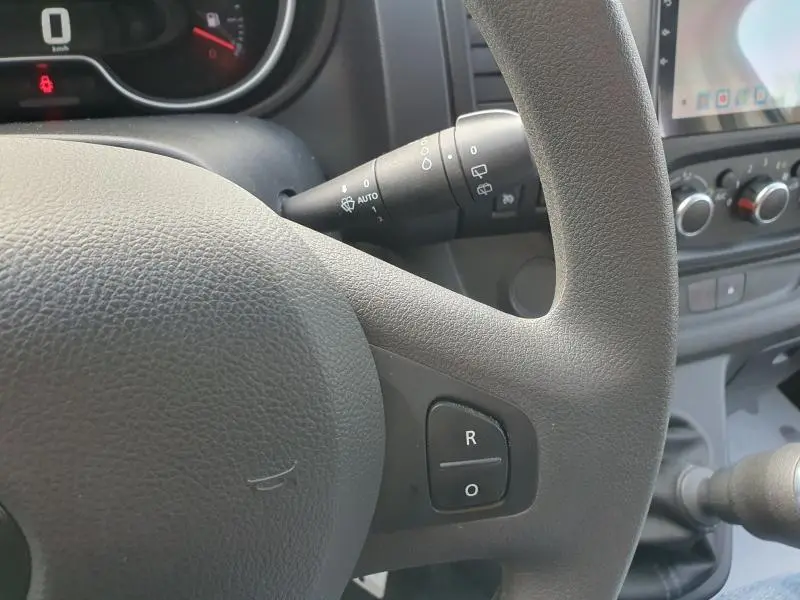 Gros plan sur le volant noir et la commande de régulateur de vitesse du Renault Trafic Fourgon blanc Glacier 2022.