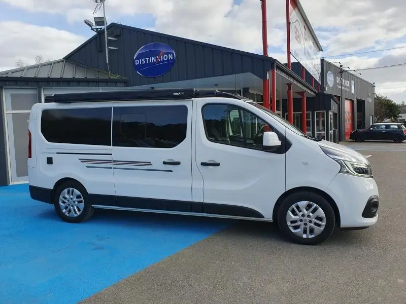 Vue latérale droite d'un Renault Trafic Fourgon blanc Glacier avec vitres arrière teintées et jantes aluminium 17 pouces.