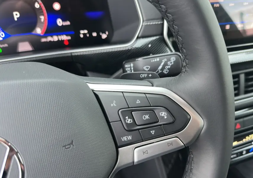 Gros plan sur le volant cuir multifonctions et le tableau de bord numérique du Volkswagen T-Cross TSI 116 DSG7 R-Line 2025.