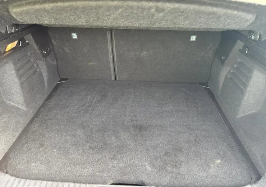 Coffre ouvert vu de l'arrière, intérieur spacieux et tapis de sol noir du Renault Symbioz bleu Iron 2025.