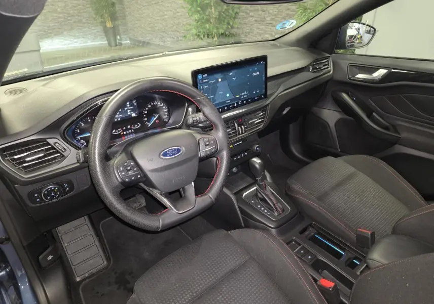 Vue intérieure avant droite de la Ford Focus 2024, volant ST à surpiqûres rouges et écran tactile 13 pouces.