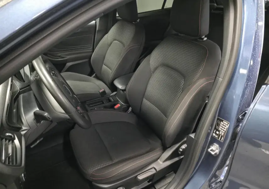 Vue intérieure côté conducteur de la Ford Focus 2024 bleu azur, sièges tissu ST-Line avec surpiqûres rouges et volant trois branches.
