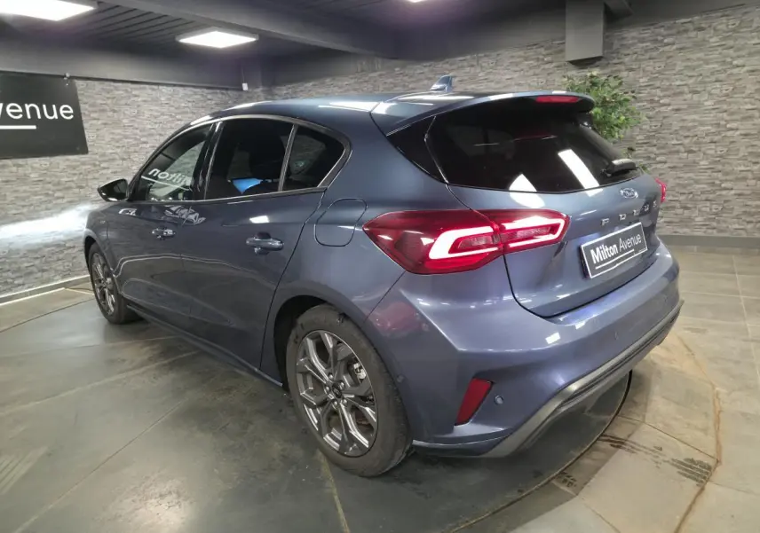 Vue 3/4 arrière droite d'une Ford Focus 2024 bleu métallisé avec feux arrière LED et jantes alliage 17 pouces.