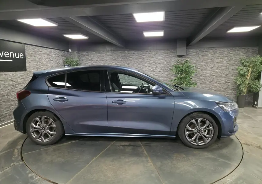 Profil droit de la Ford Focus 2024 bleu métallisé avec jantes alliage 17'' et vitres surteintées.
